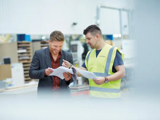 Two Jernbro employees reviewing maintenance plans together in an industrial facility.