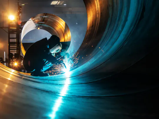 Industrial worker welding on industrial piping